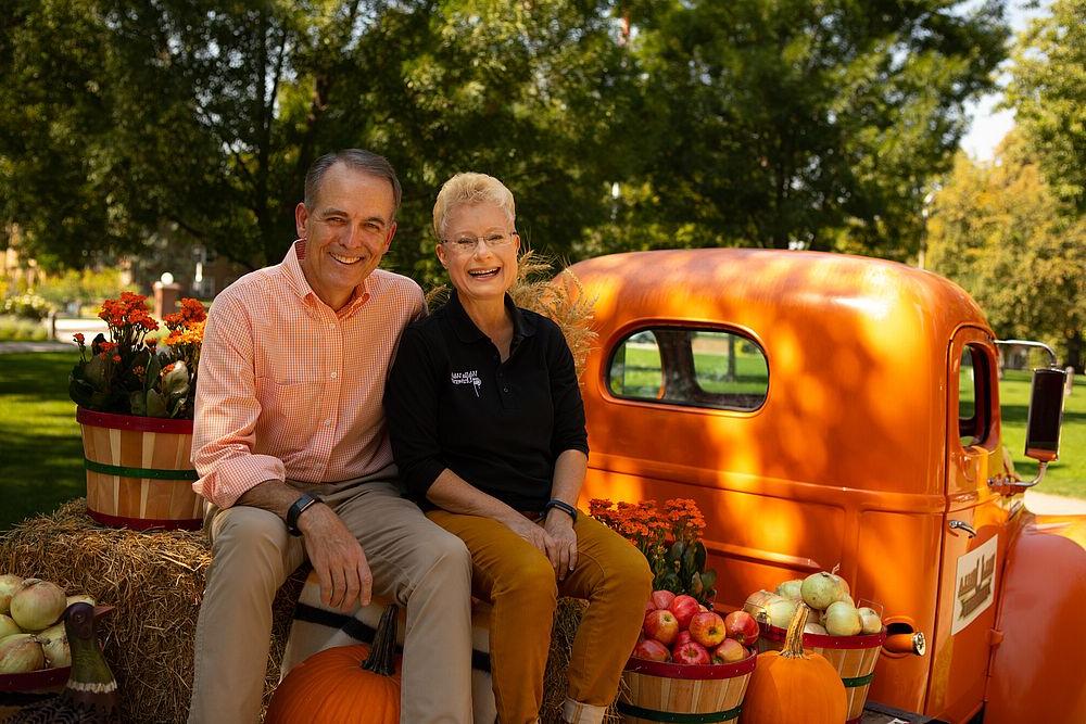 Pam and John McVay sit on truck bed decorated for fall.